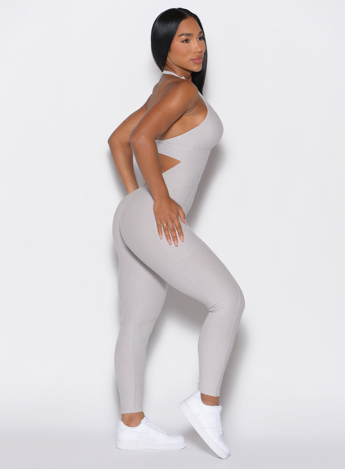 right side profile picture of a model wearing our Backless Pocket Bodysuit in ice color