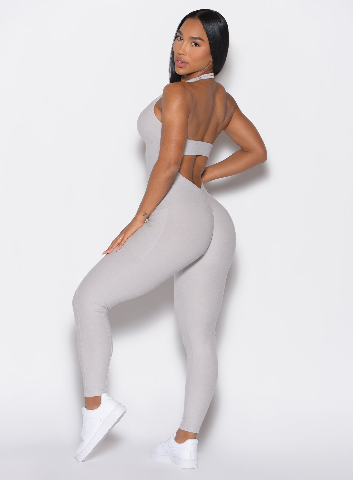 Left side profile view of a model wearing our Backless Pocket Bodysuit in ice color