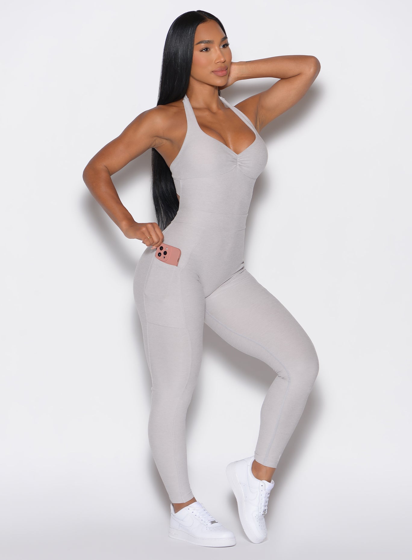 right side profile view of a model wearing our Backless Pocket Bodysuit in ice color