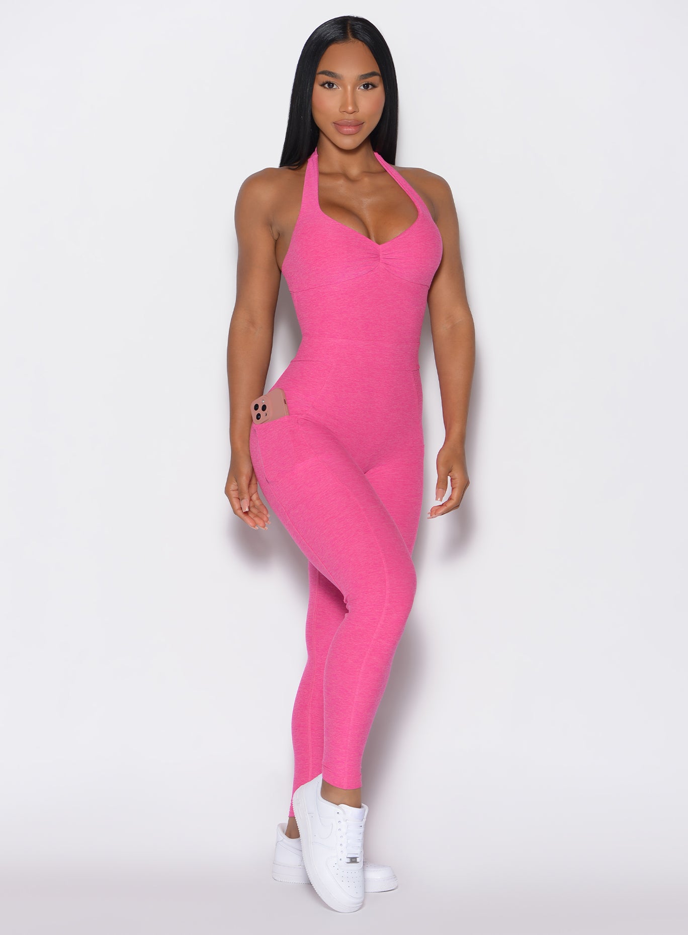 front profile view of a model facing forward wearing our Backless Pocket Bodysuit in pink glo color