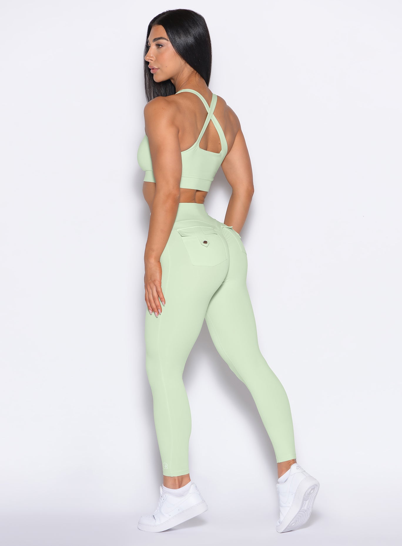 Left side view of model wearing the Pocket Pop Leggings 2.0 in Cool Matcha color and the matching bra
