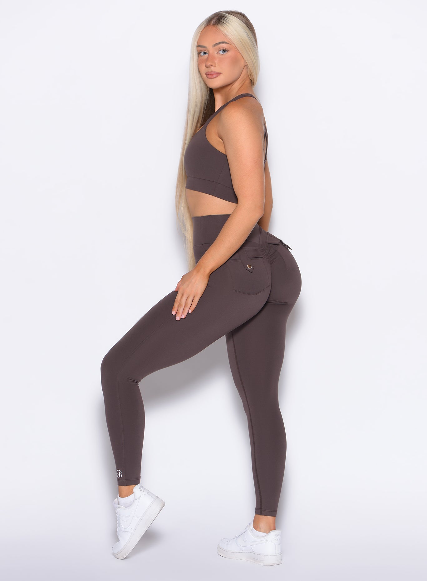 left side view of a model facing to her left wearing our Pocket Pop Leggings 2.0 in Seal Brown color and the matching bra
