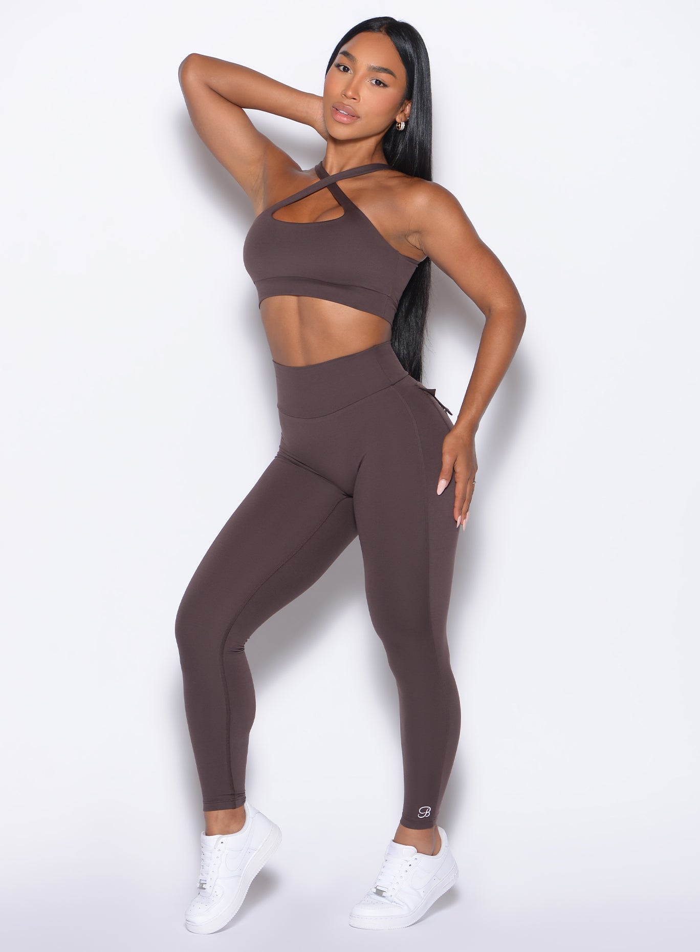 front profile view of a model posing in our Pocket Pop Leggings 2.0 in Seal Brown color and the matching bra
