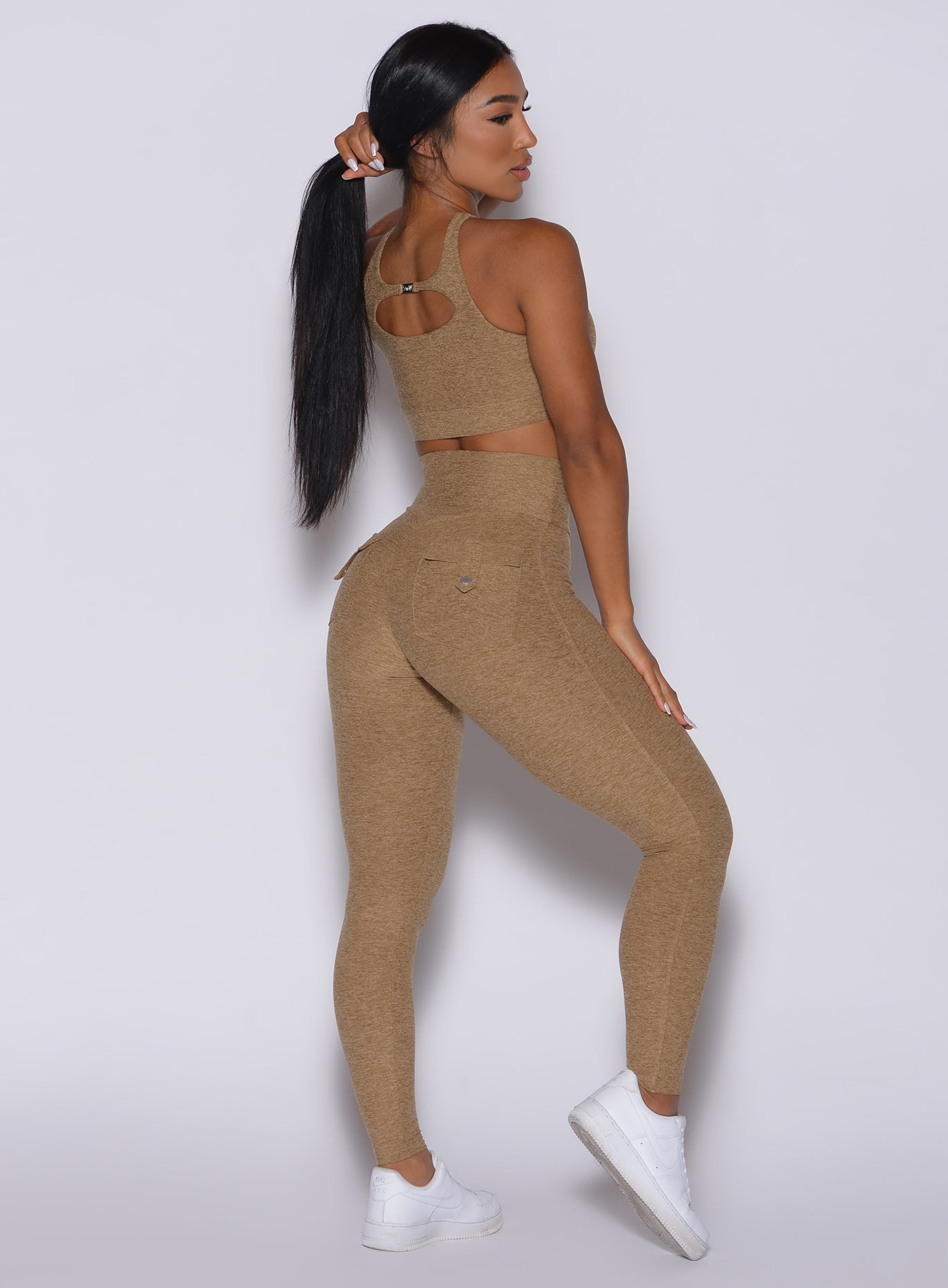 Right side profile view of a model angled slightly to her left wearing our Pocket Pop Leggings in caramel color and a matching bra