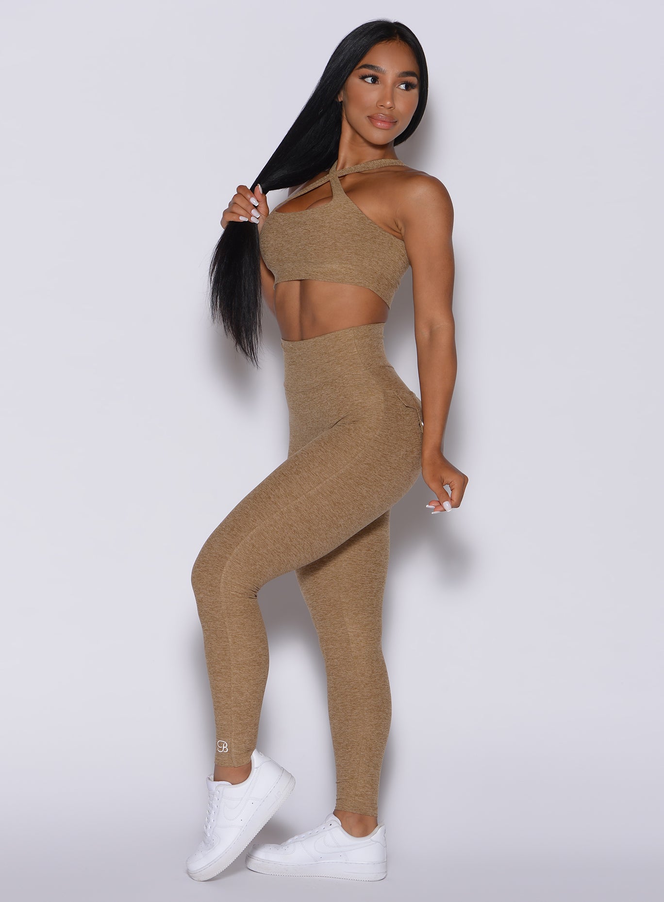 Left side profile view of a model in our Pocket Pop Leggings in caramel color and a matching bra