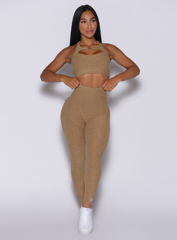 Front profile view of a model in our Pocket Pop Leggings in caramel color and a matching two way bra