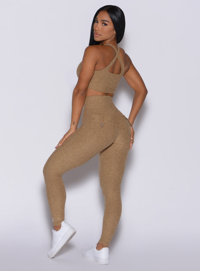 Left side profile view of a model in our Pocket Pop Leggings in caramel color and a matching two way sports bra