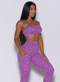 Right side profile view of a model in our pumped sports bra in purple cheetah color and matching leggings