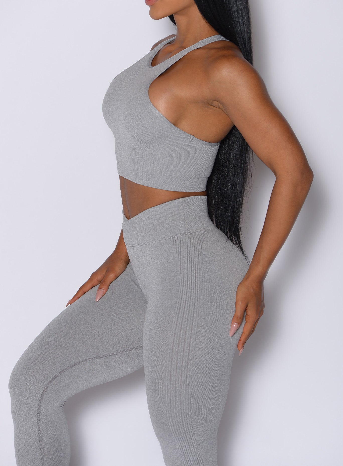 Left side profile view of a model wearing our Lifter Heather Seamless Bra and the matching leggings in Silver Mist color