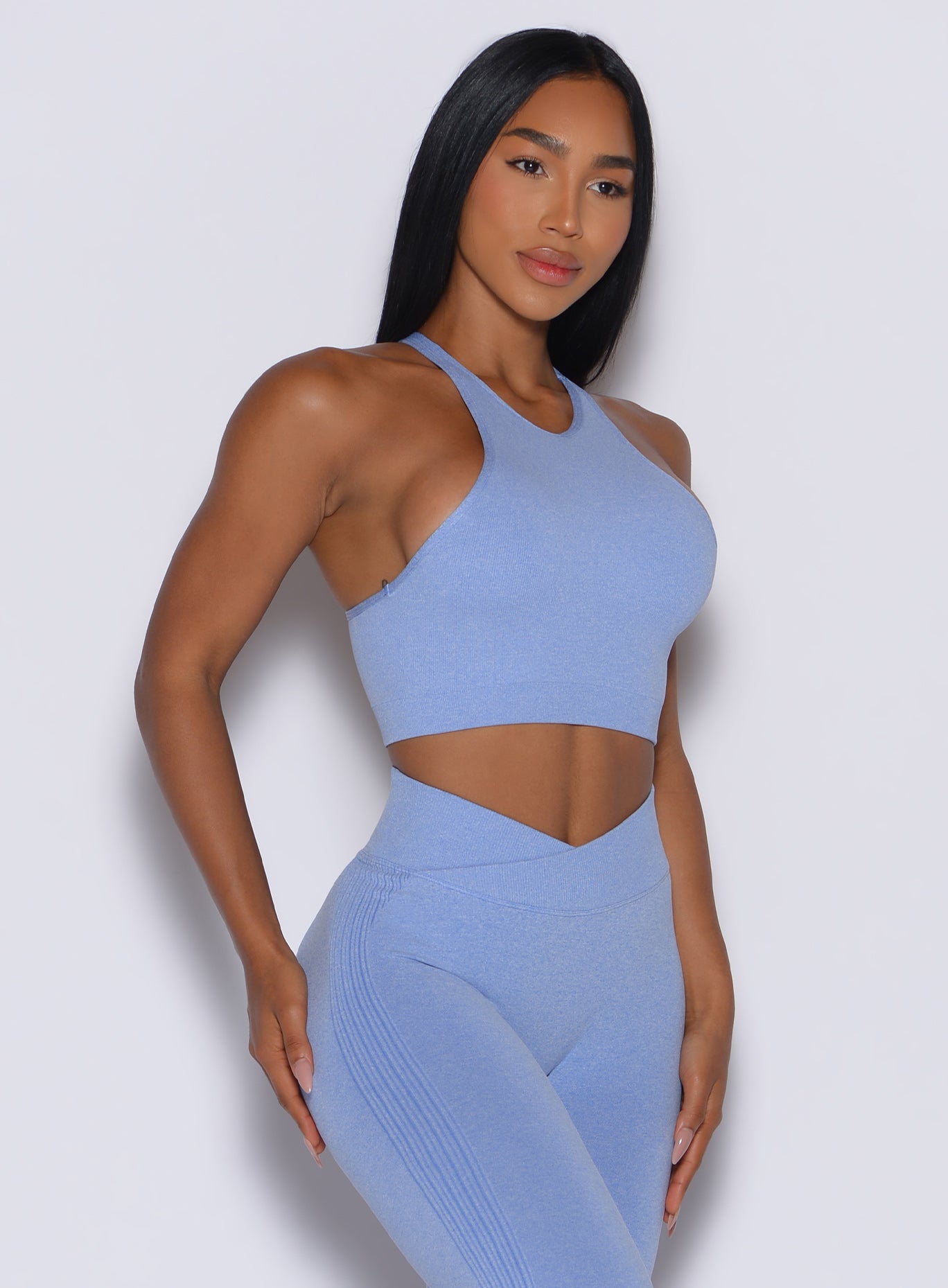 front profile view of a model posing in our Lifter Heather Seamless Bra and the matching leggings in Sky color