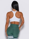 Back profile view of a model wearing our white reversible tank bra along with a thigh high in emerald green color 