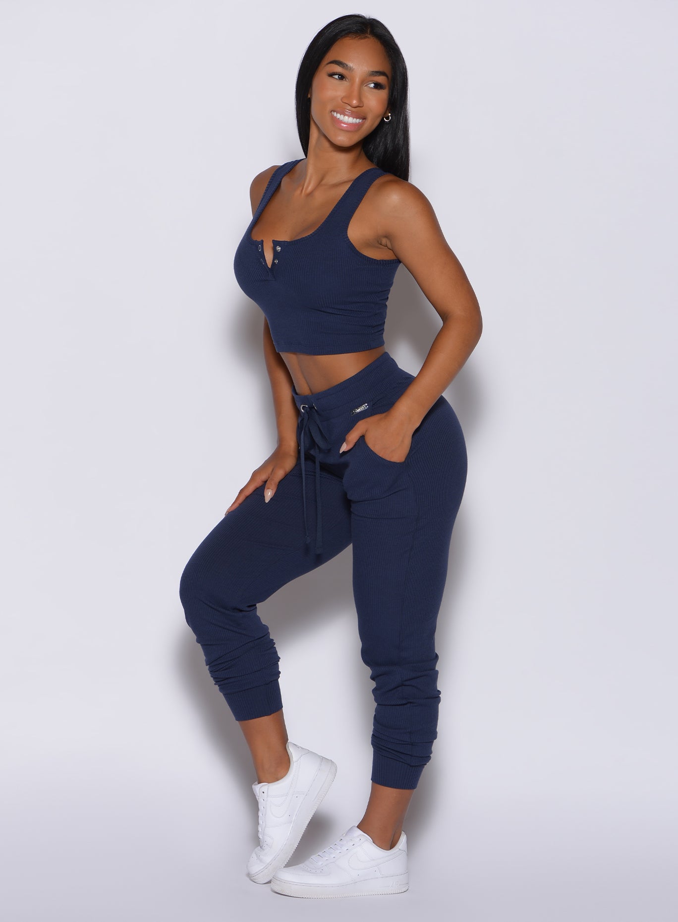 Left side profile view of a model angled left wearing our comfort rib joggers in navy and a matching bra