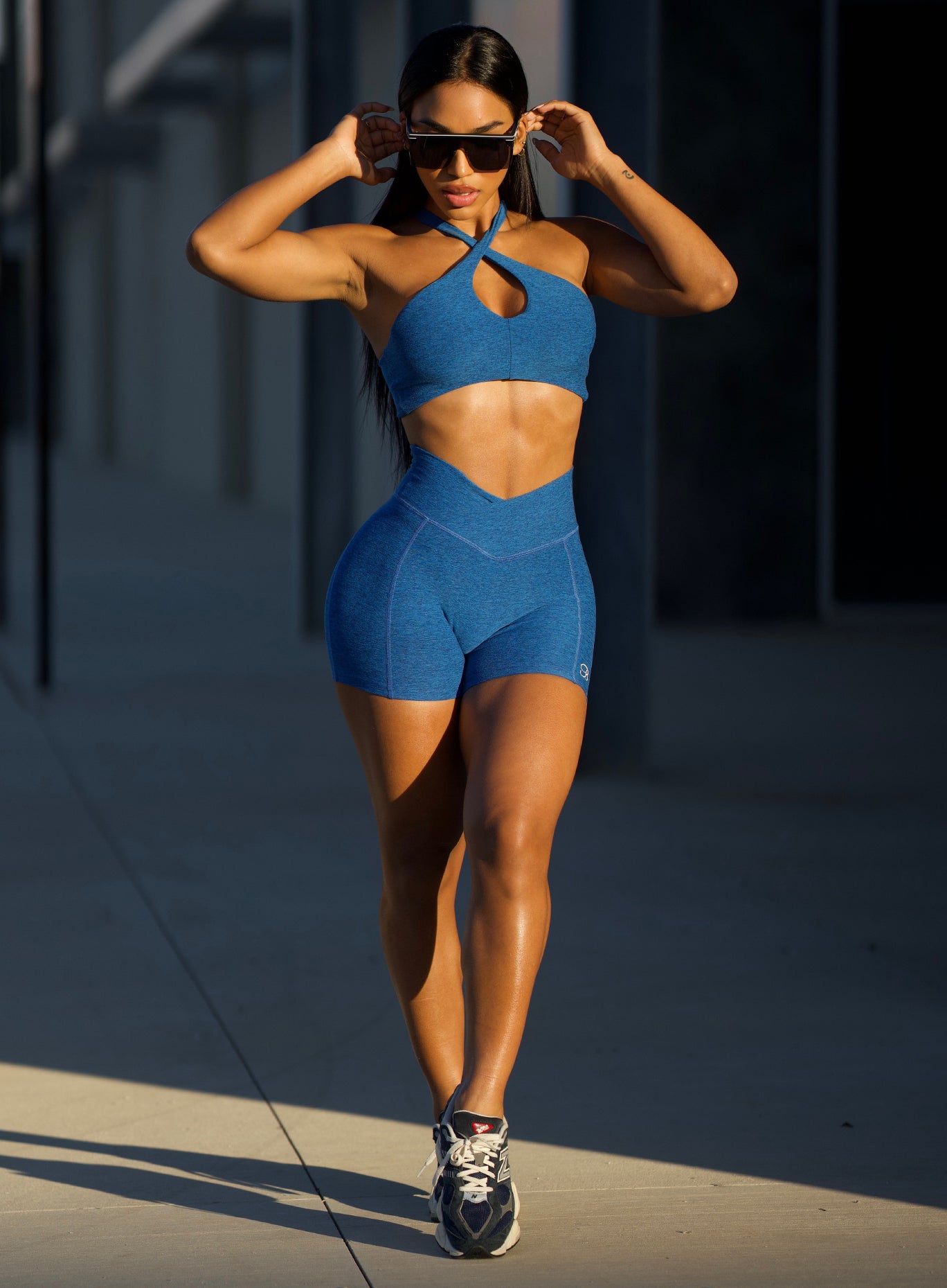 front profile picture of a model in outdoor wearing our Tiny Waist Shorts and the matching Asymmetrical Slit Bra in Royal color