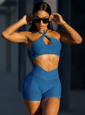 front view of a model posing in outdoor wearing our Cross Over Halter Bra and the matching leggings in Royal color
