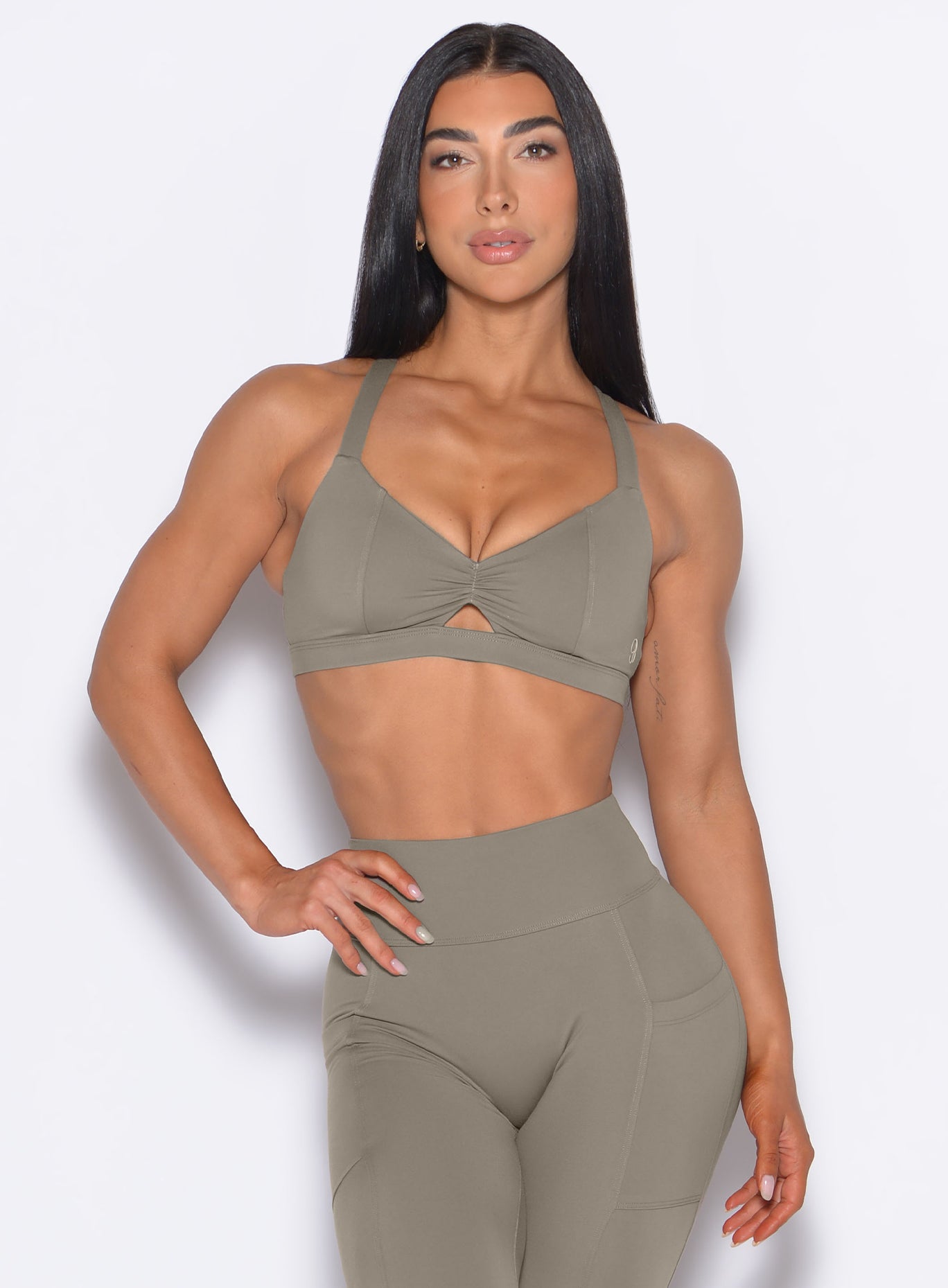 front profile view of our model with one hand on the waist wearing the Sweetheart Sports Bra in Stone color