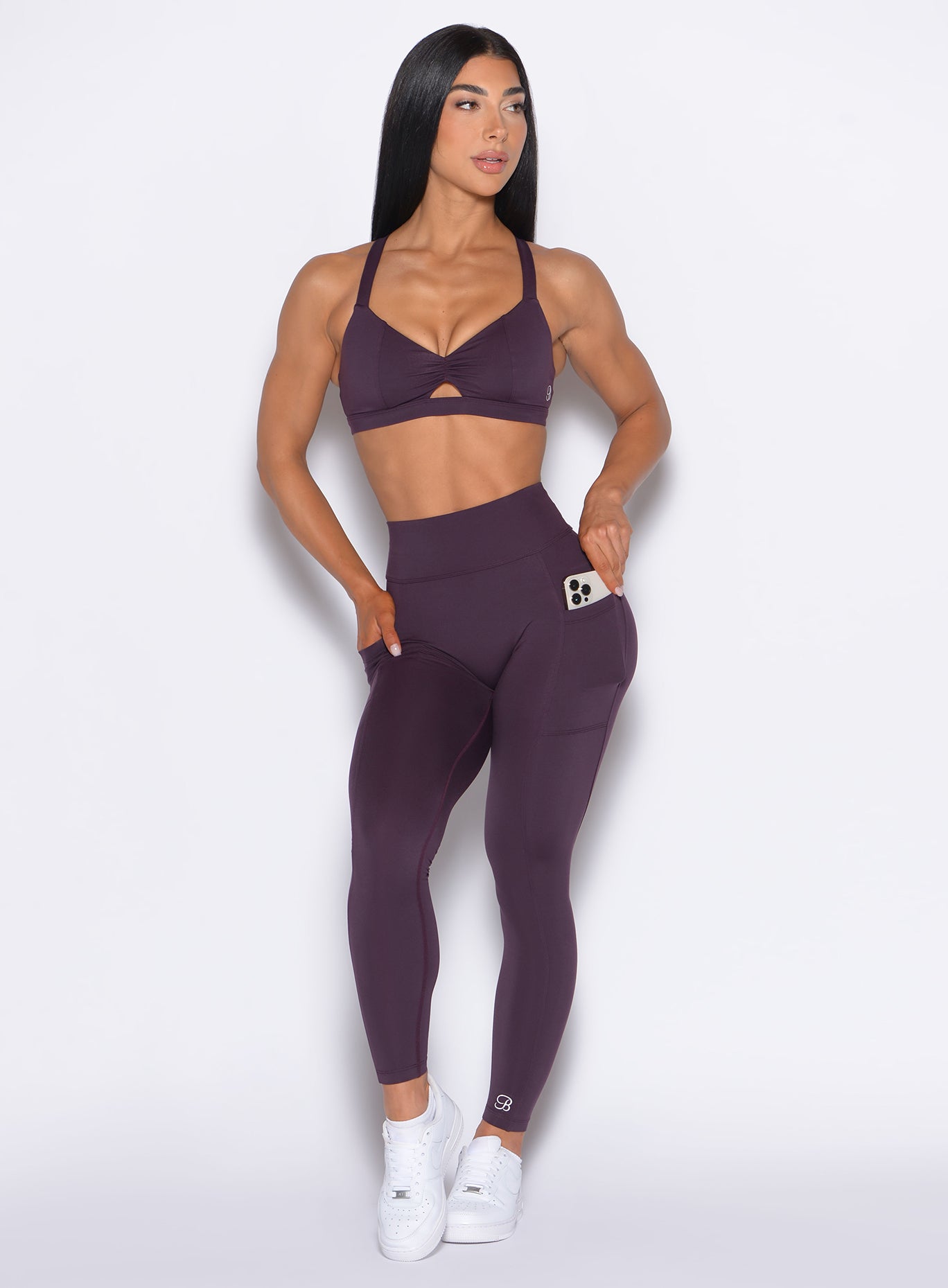 Front profile view of our model with her right hand inside the pocket of the leggings and looking to the left wearing our Define Leggings in Plum Noir color