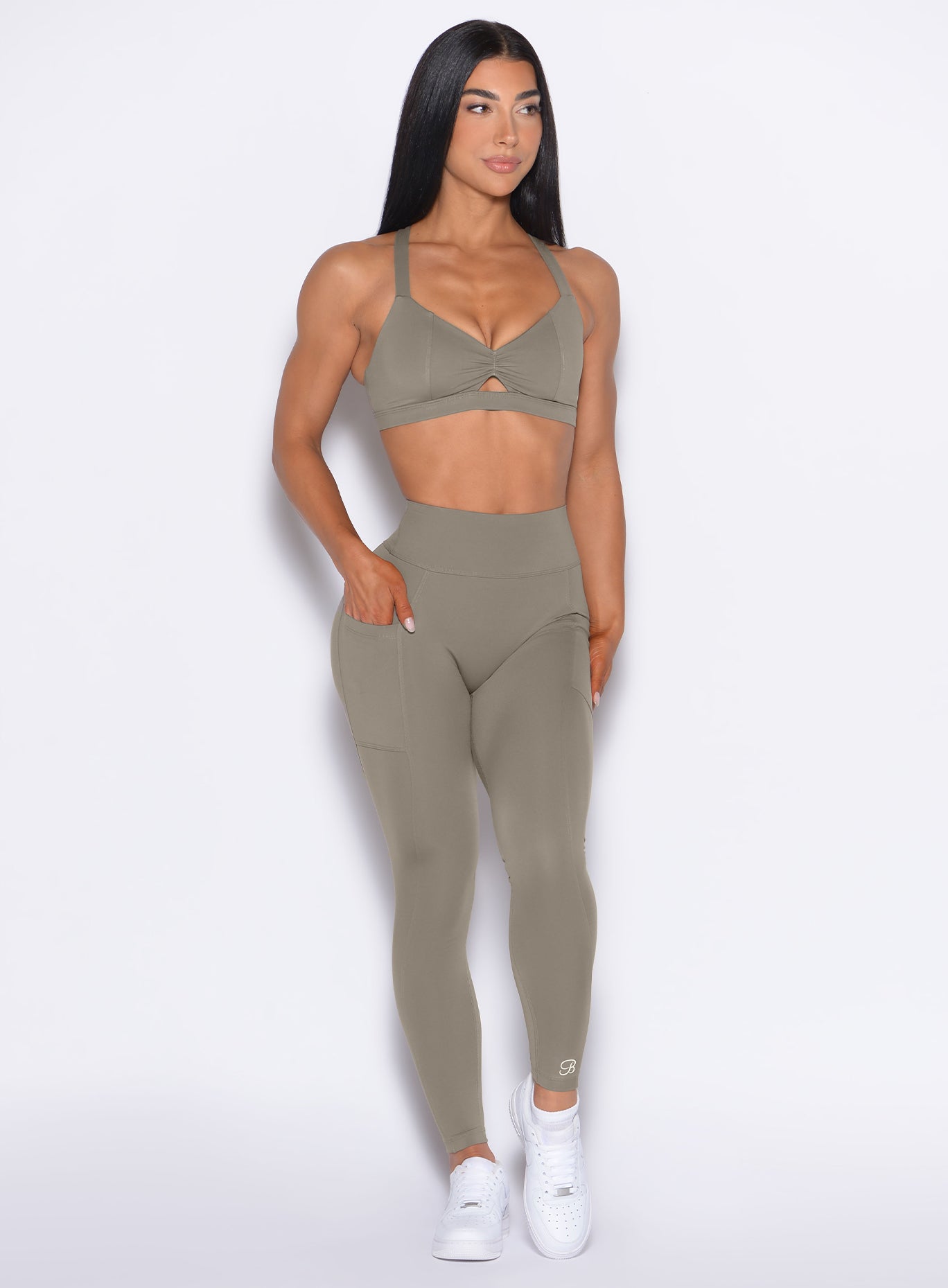 front profile view of our model looking to the right with one hand inside the pocket of the leggings wearing our Define Leggings in Stone color