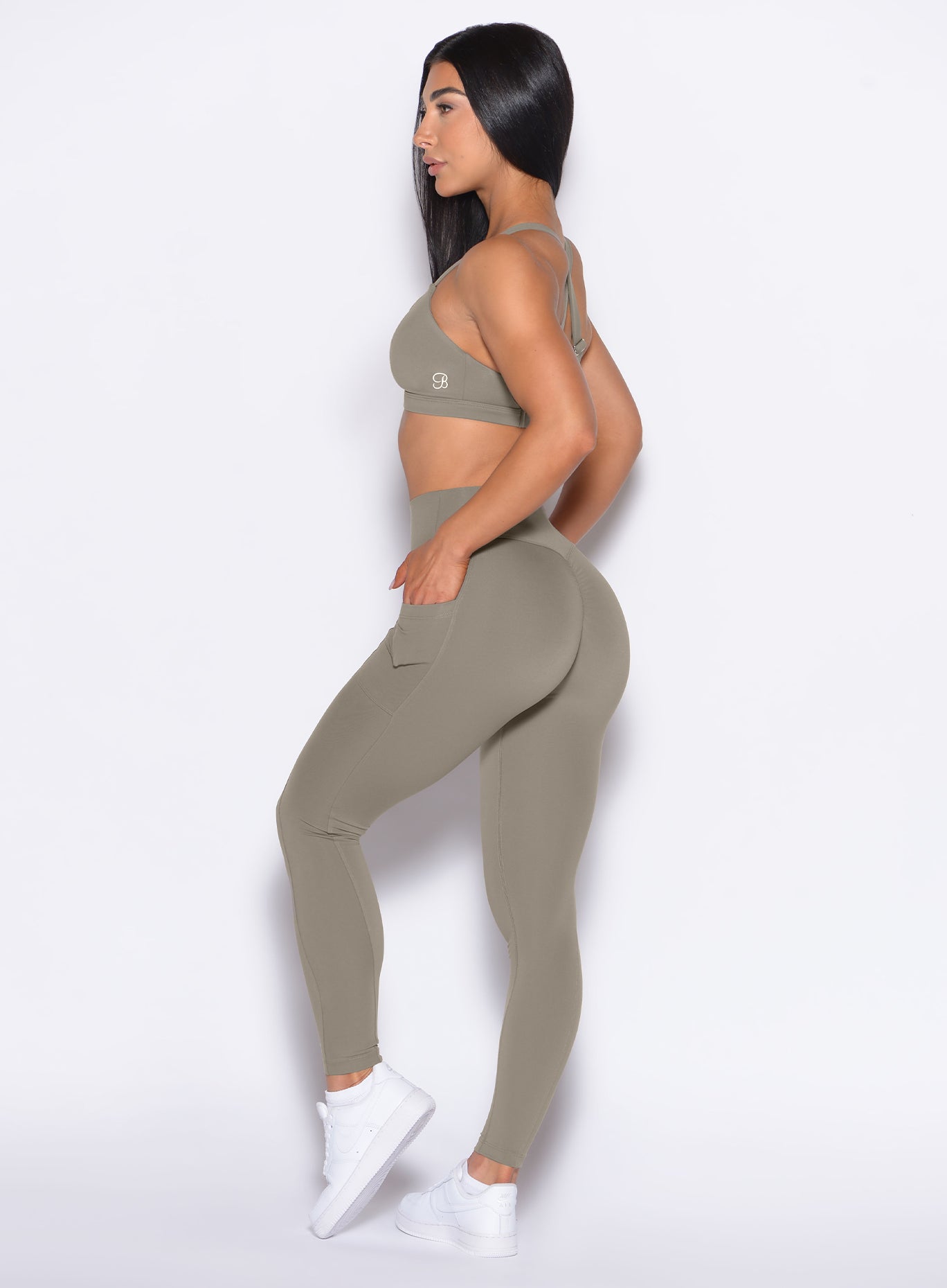 Left side profile view of our model with her hands inside the pocket of the leggings wearing the Define Leggings in Stone color