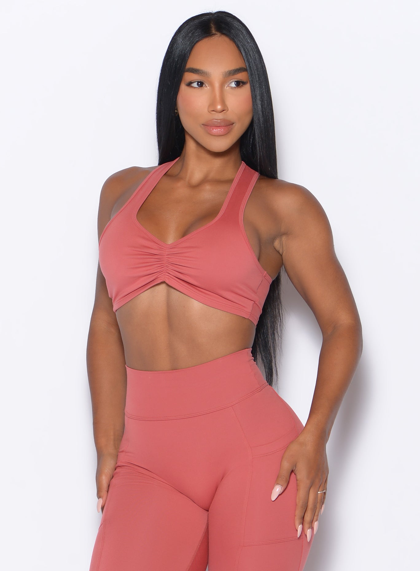 Front profile view of our model looking to the left wearing the Scrunch Tank Bra in Terracotta color paired with the matching leggings