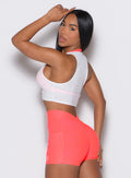 Left side profile view of a model wearing our white Butterfly Rib Tank on the top of a pink sports bra