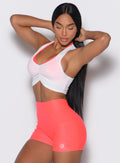 front profile view of a model holding her hair wearing our white Butterfly Rib Tank on the top of a pink sports bra