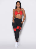 Front profile view of a model wearing the Scrunch Thigh Highs in Black Fire color along with a red sports bra