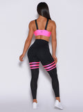 Back  profile view of a model in our black scrunch thigh high with neon pink stripes on the thighs and a matching glow sports bra