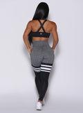 Back profile view of a model in our scrunch thigh high in gray and black with three stripes on the thighs and a matching black bra 