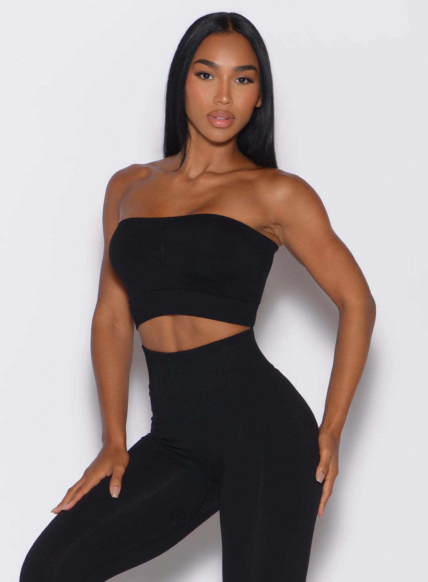 front profile picture of a model facing forward, wearing our black seamless bandeau along with the matching leggings