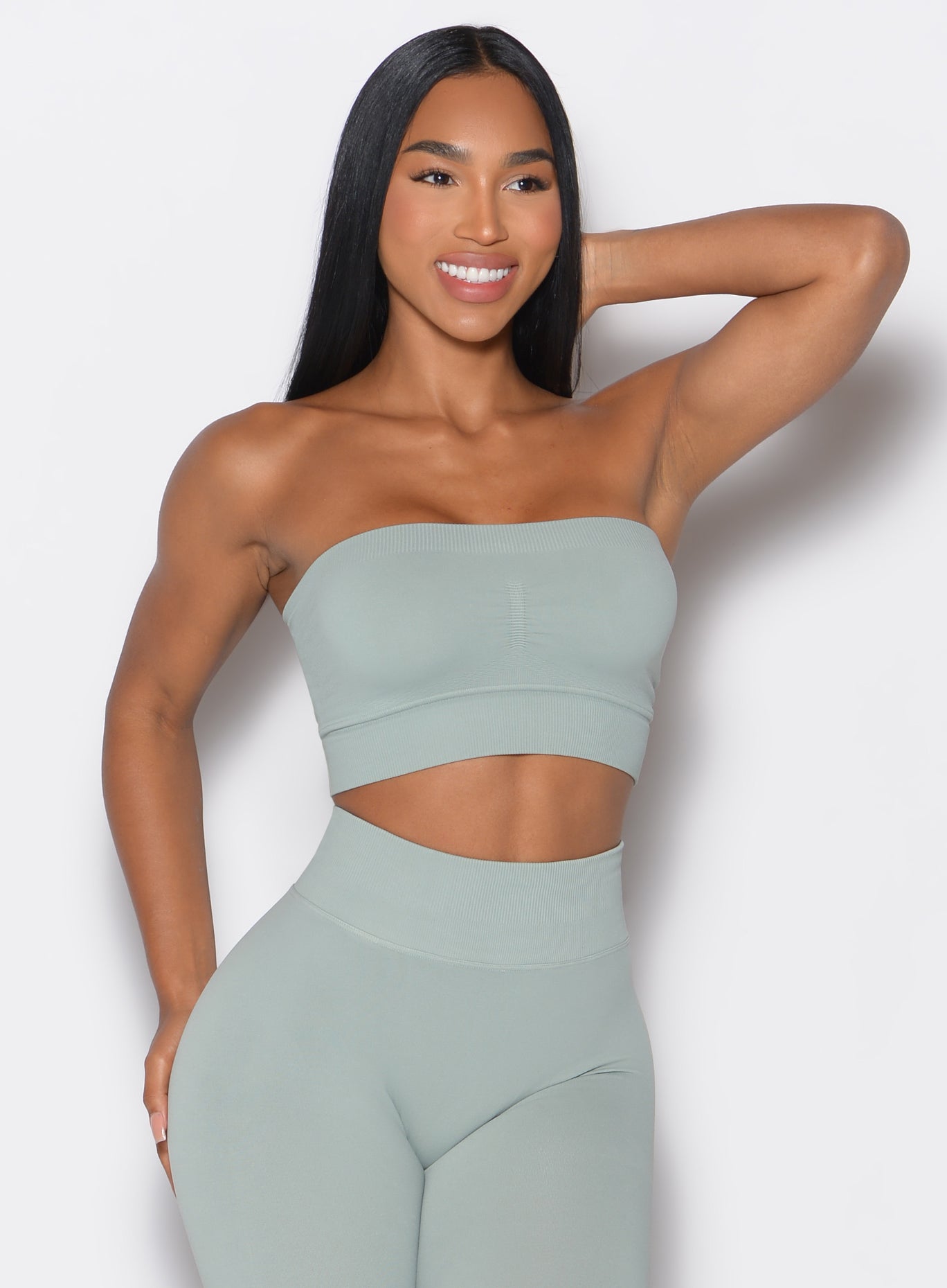 front profile view of a model wearing our seamless bandeau in light jade color along with the matching leggings