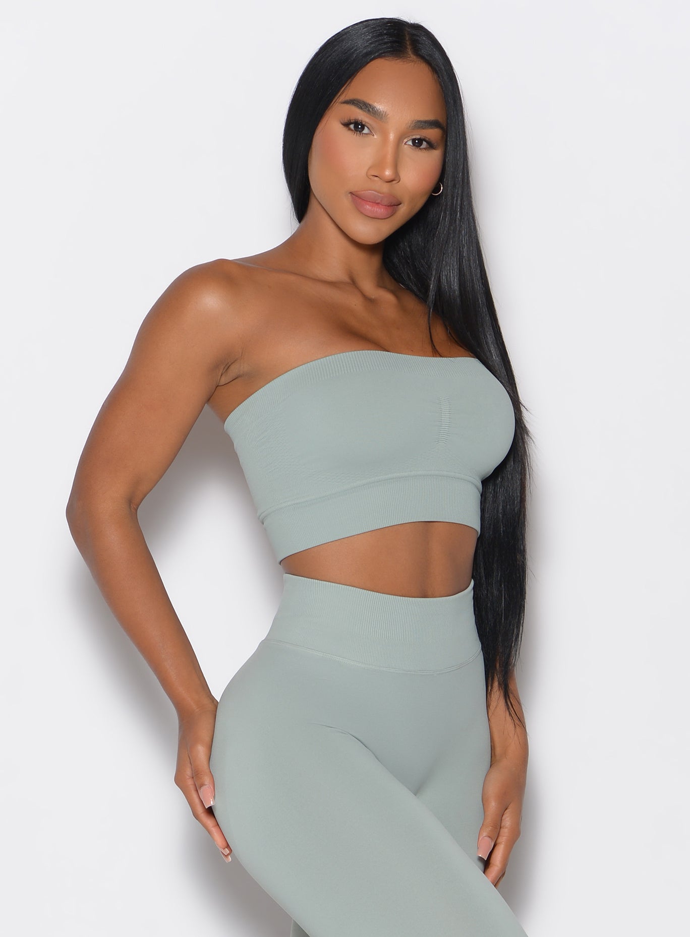right side profile view of a model wearing our seamless bandeau in light jade color along with the matching leggings