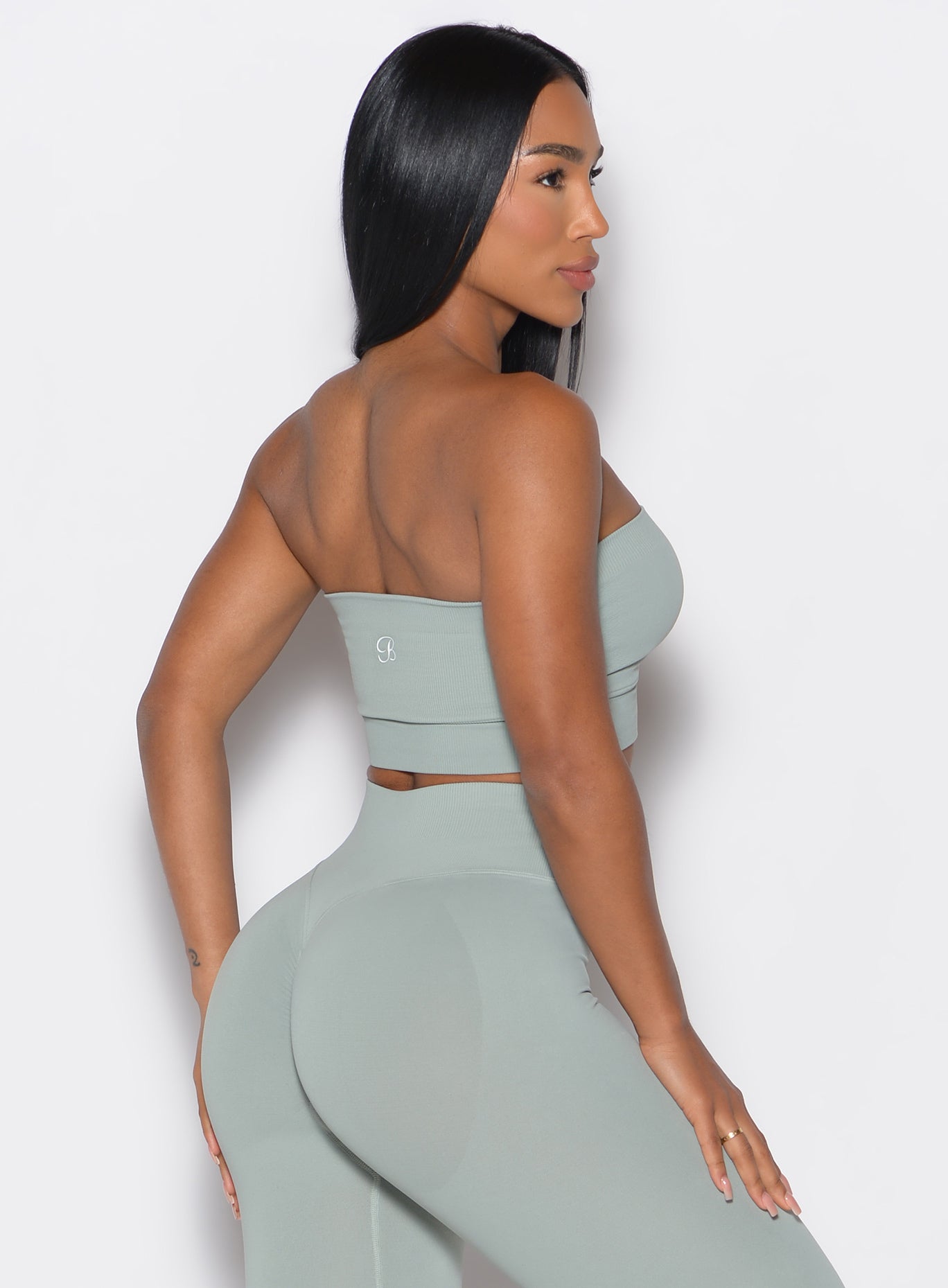 back profile view of a model wearing our seamless bandeau in light jade color along with the matching leggings