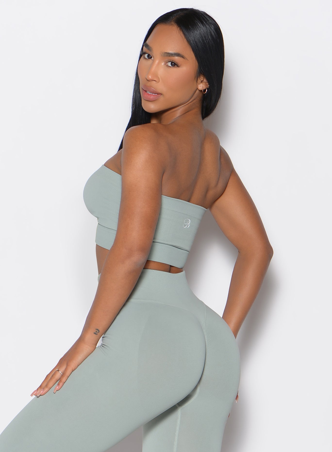left side profile view of a model wearing our seamless bandeau in light jade color along with the matching seamless leggings