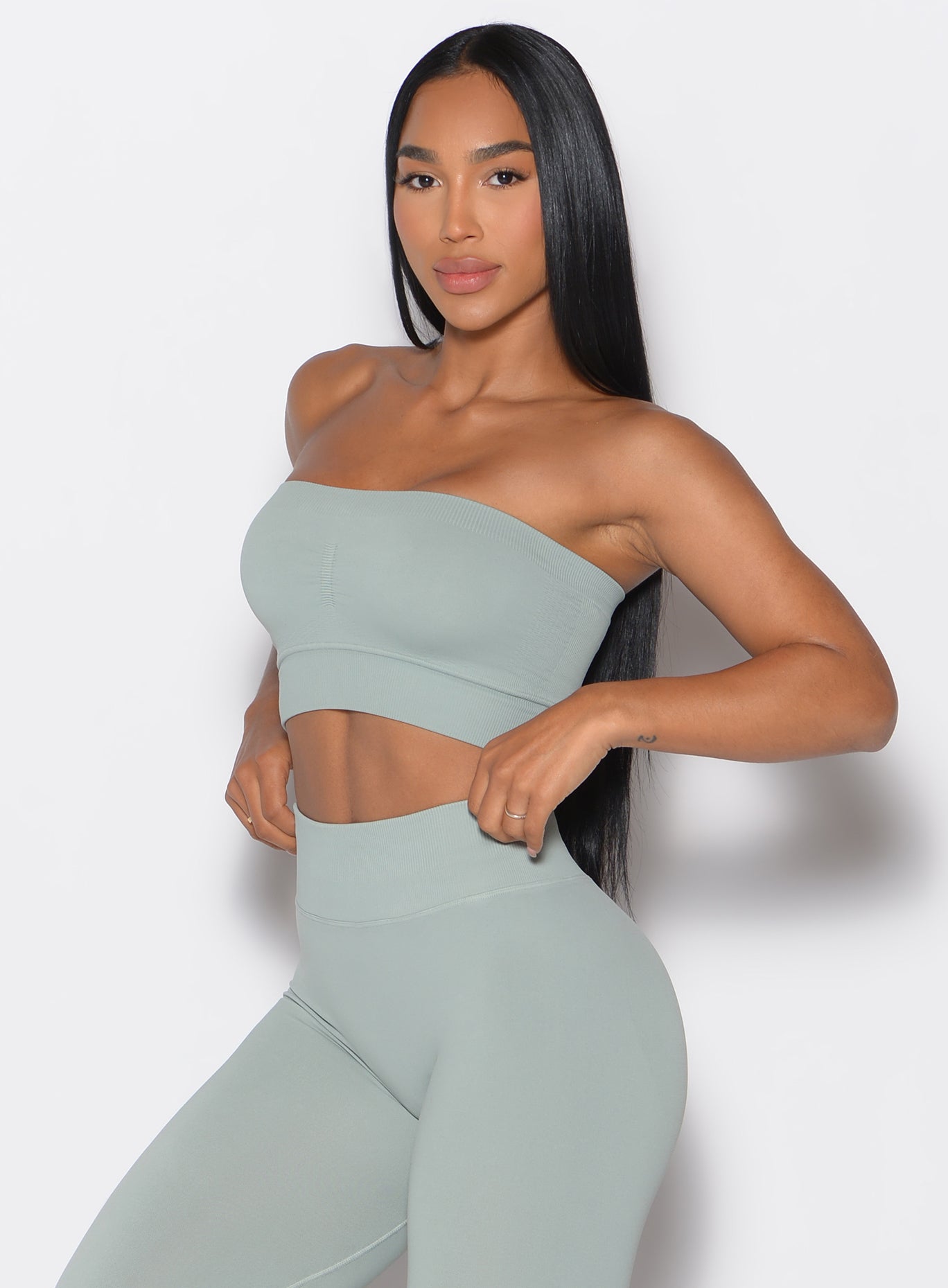 front profile view of a model facing forward wearing our seamless bandeau in light jade color along with the matching leggings