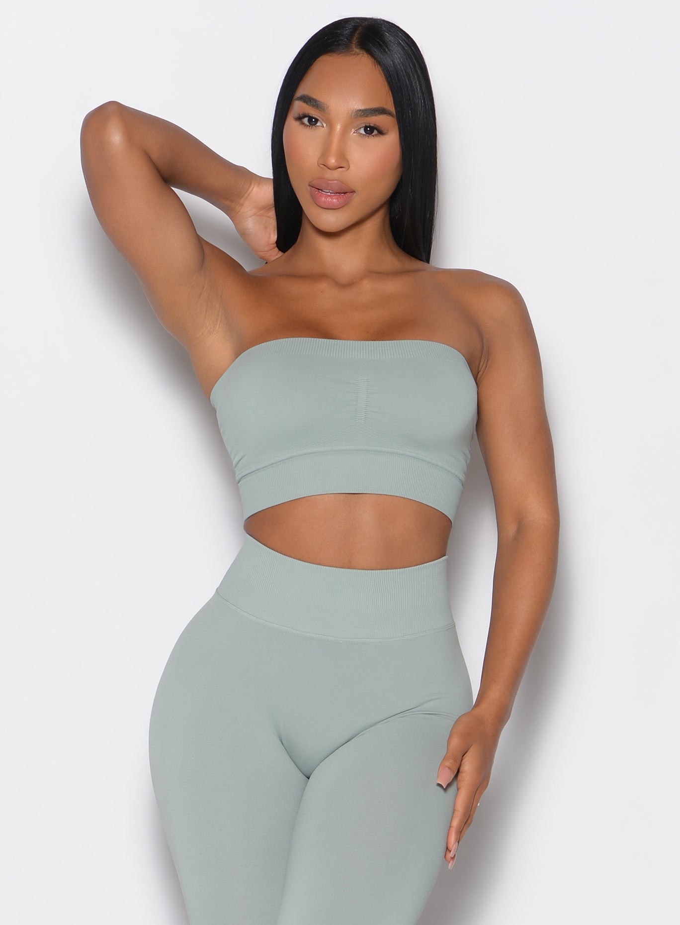 front profile picture of a model wearing our seamless bandeau in light jade color along with the matching seamless leggings