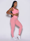 Right side profile view of our model  with both hands on the waist of the leggings wearing the Figure Leggings in Peach Burst color