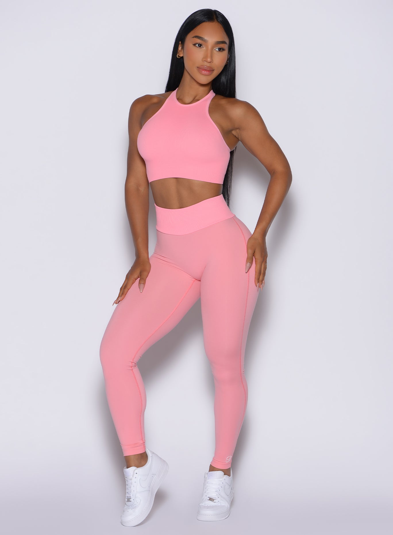 Front profile view of our model looking to the left wearing the Figure Scrunch Leggings in Peach Burst color with the matching top