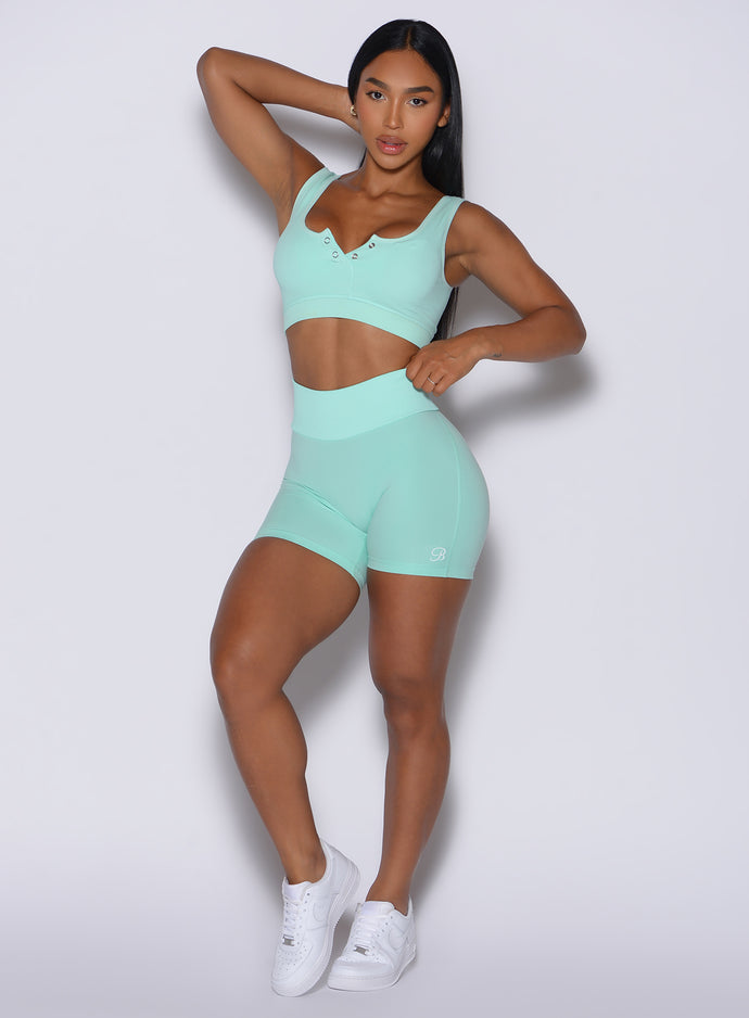 Front profile view of our model with one hand resting on the back of her head wearing the Figure Scrunch Shorts in Spring Mint color