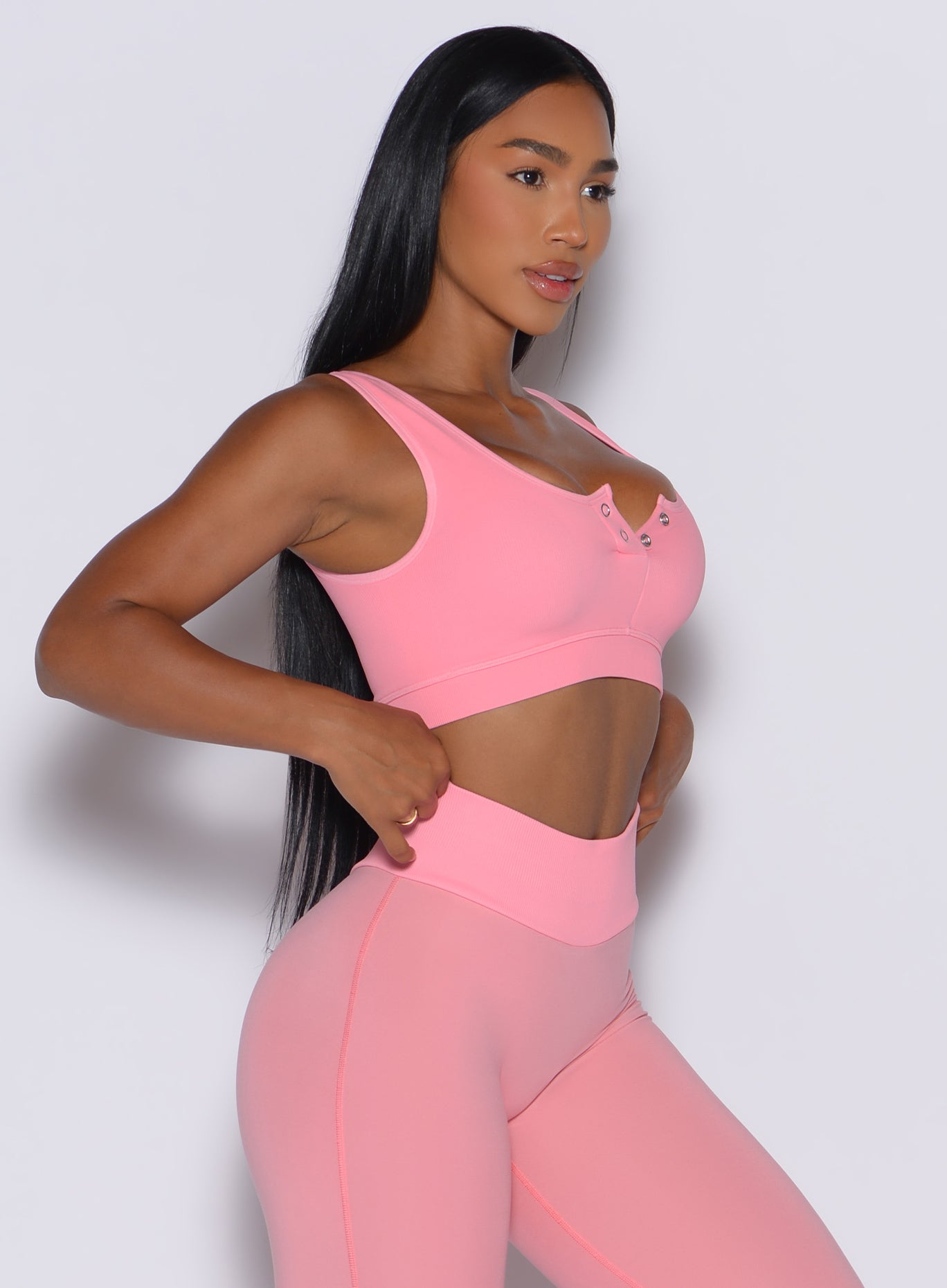 right side profile view of a model facing forward wearing our Snap Seamless Bra and the matching leggings in Peach Burst color