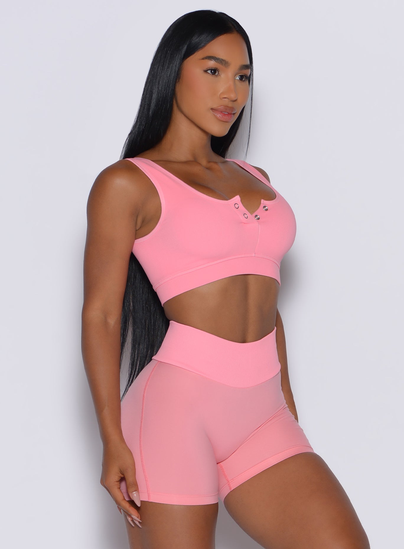 right side profile view of a model facing forward wearing our Snap Seamless Bra and the matching shorts in Peach Burst color