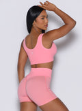 Right side view of a model facing to her right wearing our Snap Seamless Bra and the matching shorts in Peach Burst color