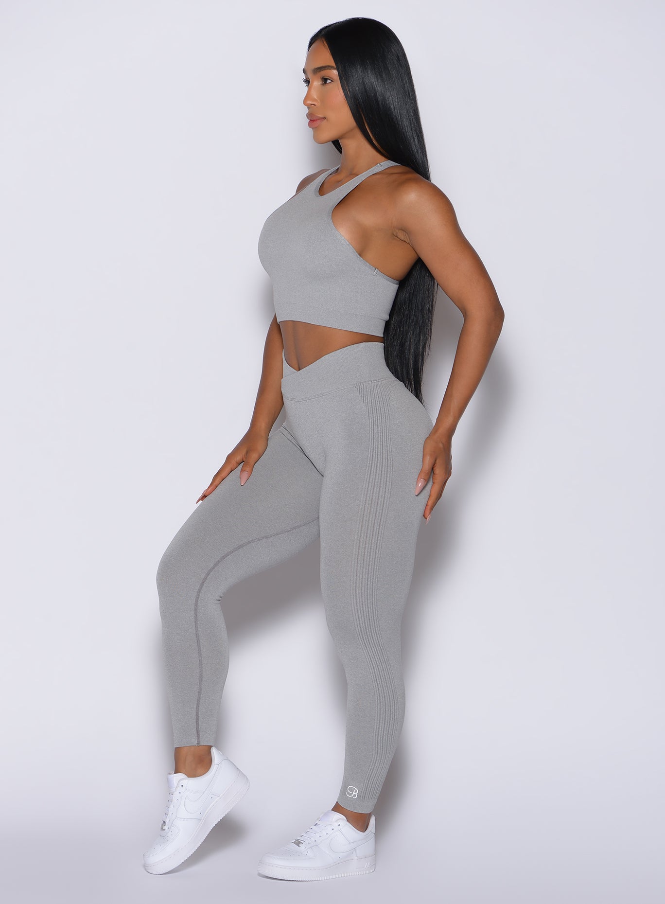 left side profile view of a model facing forward wearing our Contour Seamless Leggings and the matching Lifter Heather Seamless Bra in Silver Mist color