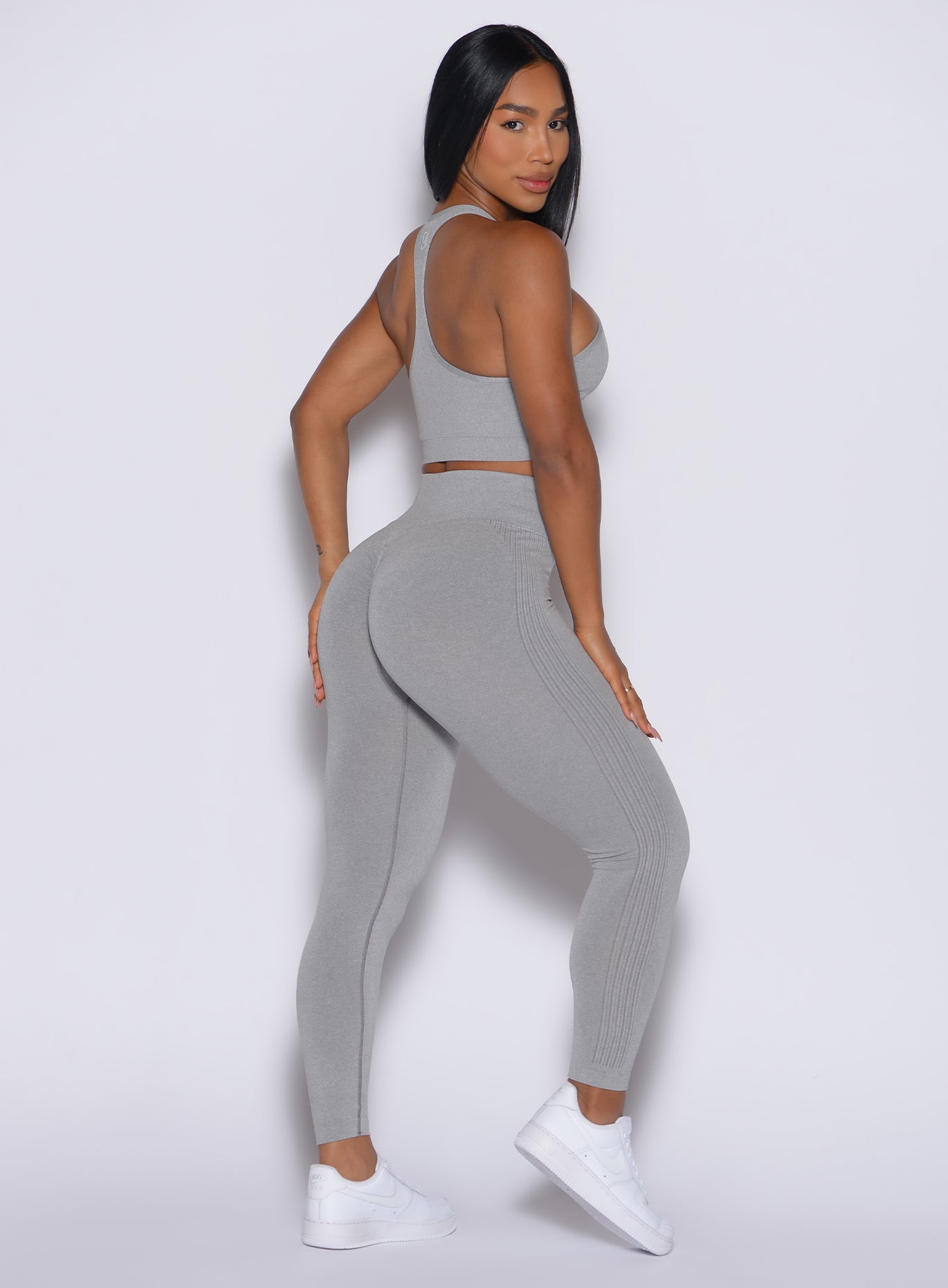 Right side view of a model facing to her right wearing our Contour Seamless Leggings and the matching Lifter Heather Seamless Bra in Silver Mist color