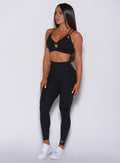 Front profile view of a model facing to her right wearing our new and enhanced black shape leggings and a matching bra