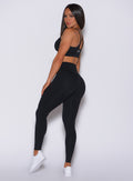 Left side profile view of a model in our new and enhanced black shape leggings and a matching bra