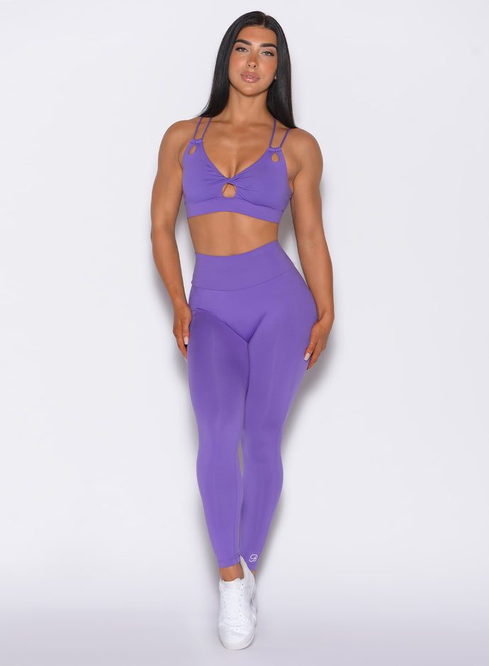 Front profile view of a model wearing our shape leggings in royal purple color along with the matching sports bra