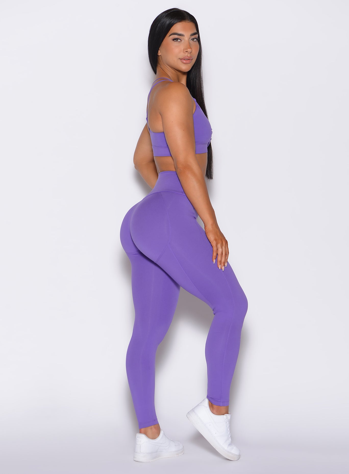 right side profile view of a model wearing our shape leggings in royal purple color along with the matching sports  bra