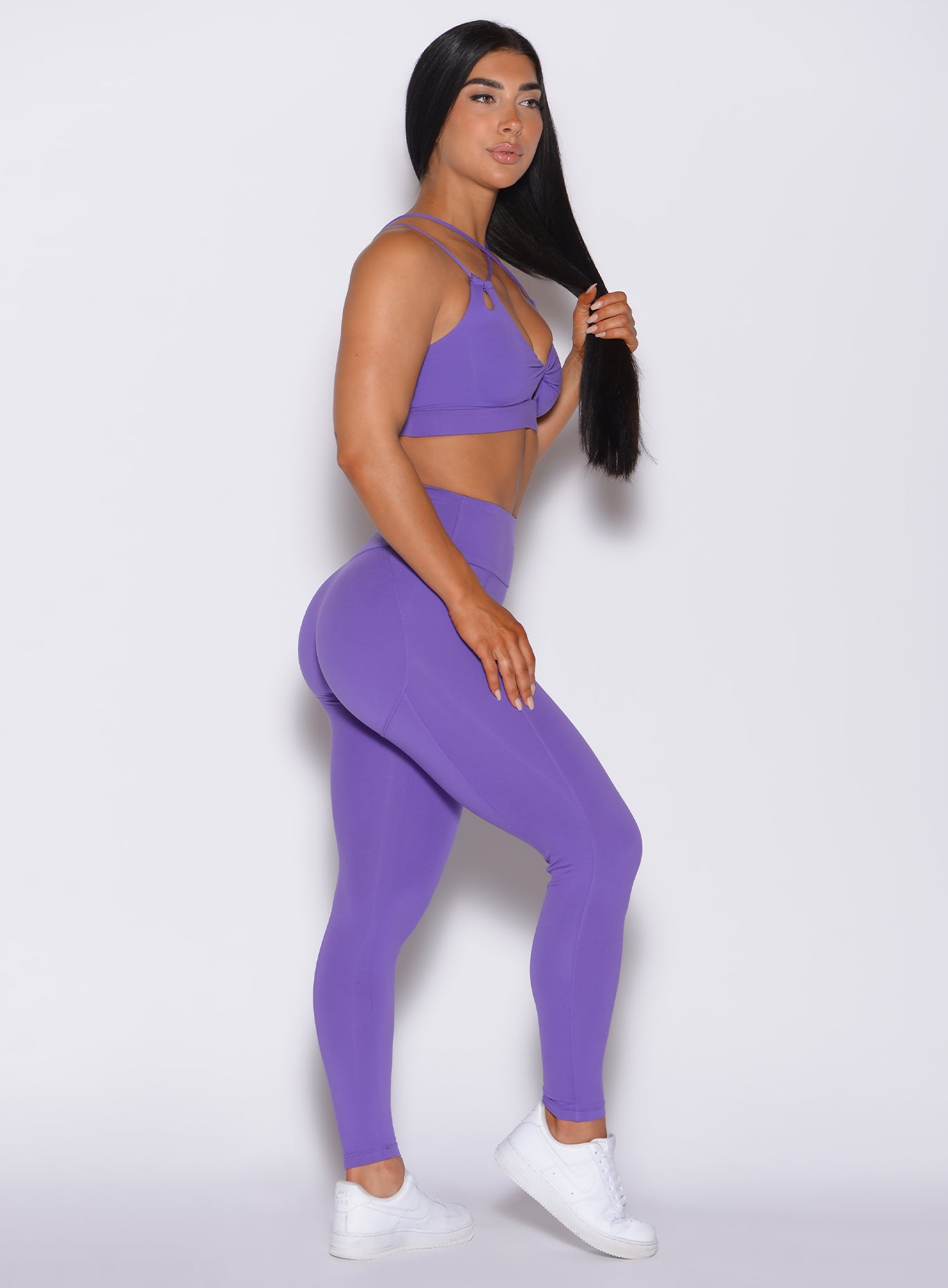 right side profile view of a model facing forward wearing our shape leggings in royal purple color along with the matching bra