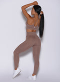 Back profile picture of a model wearing our new and enhanced shape leggings in tan color and a matching bra