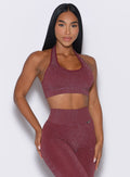 front profile view of a model with both hands resting on her thighs wearing the Shimmer Backless Bra in Ruby star color